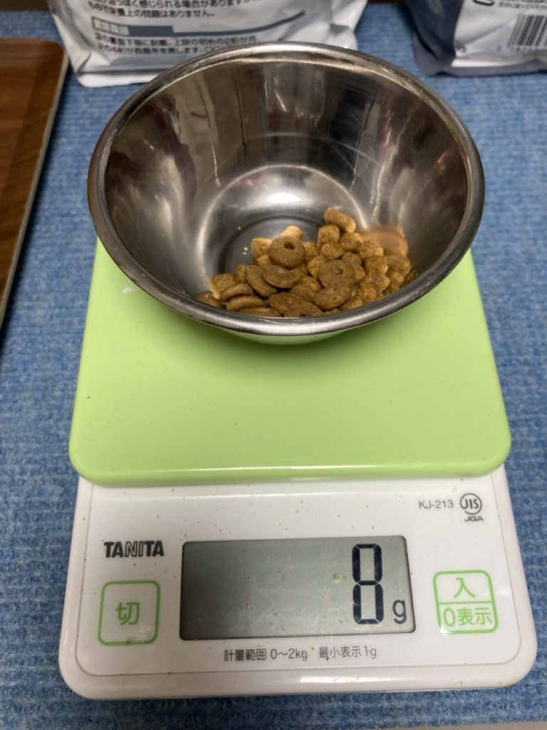 猫のドライフードをキッチンスケールで計量している様子